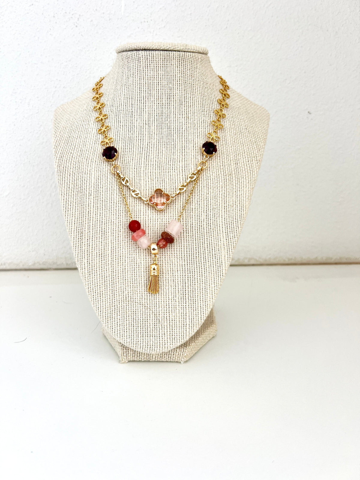 Gold-plated mixed-chain statement necklace with blush-toned crystal connectors, peach clover and tassel