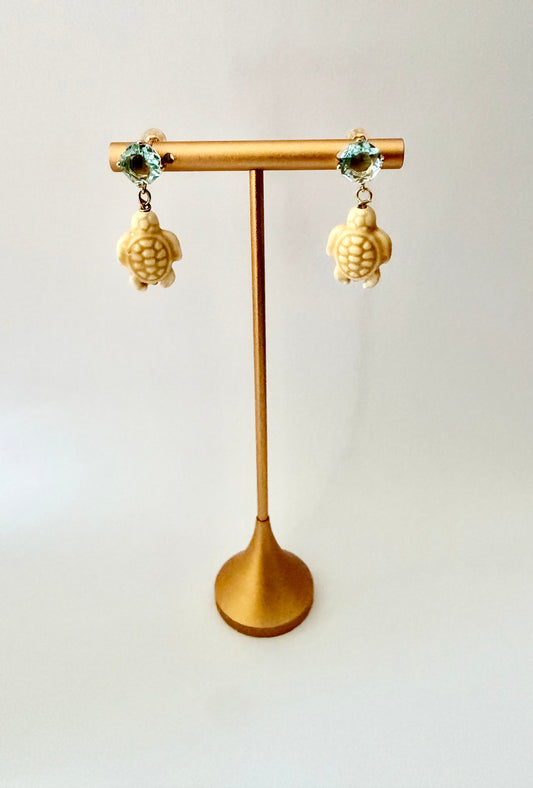 Gold-plated earrings with pale blue cubic zirconia posts and neutral ceramic turtle charms